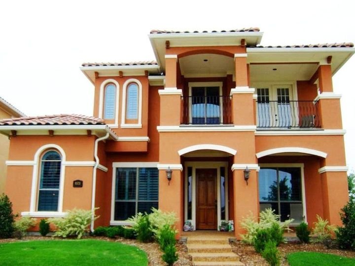 Terracotta stucco house with cream trim, arches and a clay tile roof