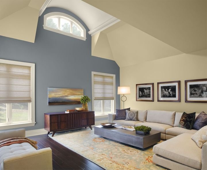 Vaulted living room with a slate blue accent wall, cream walls and ceiling and white trim